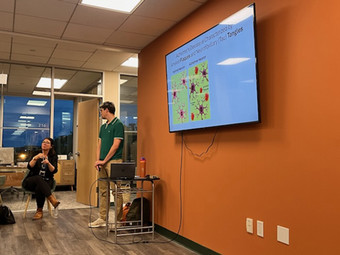 Dr.anne Berry seated infront of the room. Dr. Tom Morrin standing infront of the room presenting with the powerpoint showing behind him.